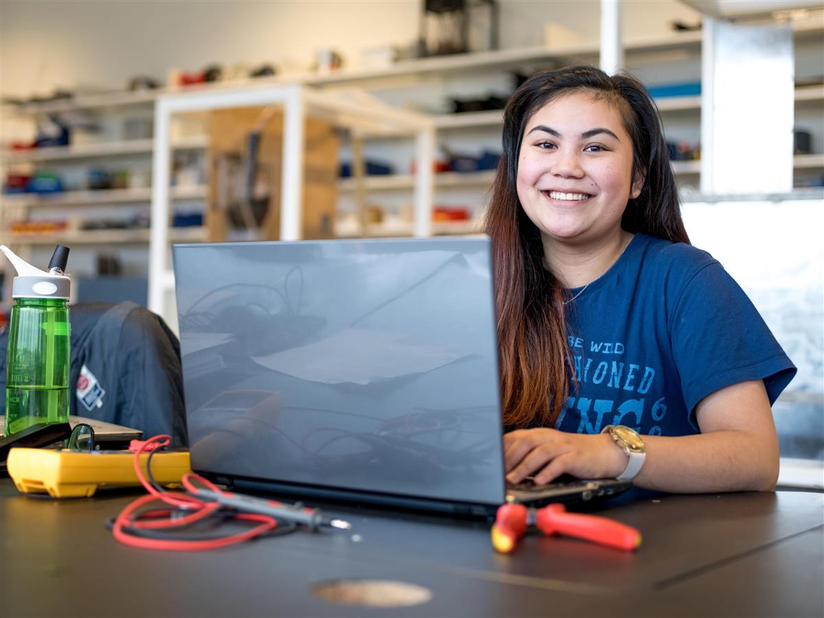 Smilende jente som sitter med en datamaskin  - Klikk for stort bilde