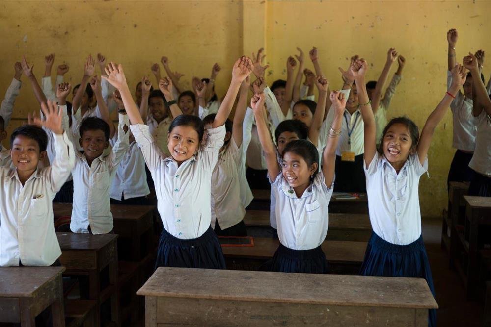 Mange elever i klasserom i Kambodsja som strekker hendene over hodet - Klikk for stort bilde